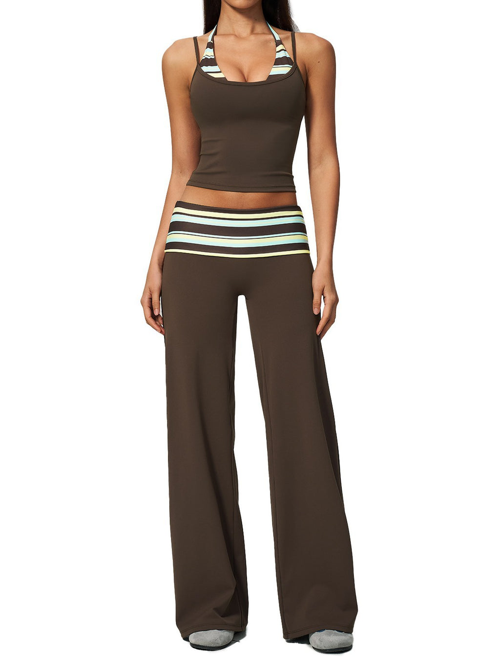 A woman modeling a matching two-piece lounge set consisting of a brown cropped tank top with striped halter straps and matching wide-leg pants with a striped waistband.